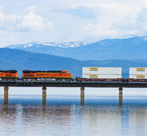 BNSF locomotives travelling across a bridge above water.