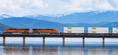BNSF locomotives travelling across a bridge above water.