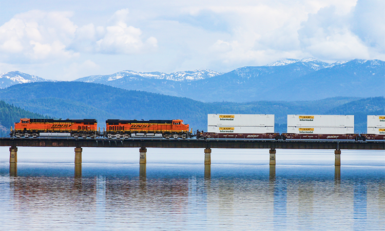 BNSF locomotives travelling across a bridge above water.