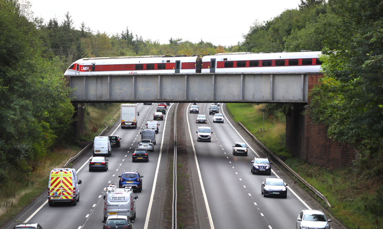 LNER train travelling over a motorway