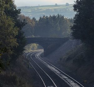 Empty rail track passing beneath a bridge in the English countryside.