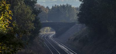 Empty rail track passing beneath a bridge in the English countryside.