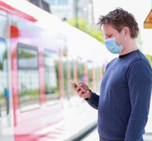 Man standing on train platform wearing face mask