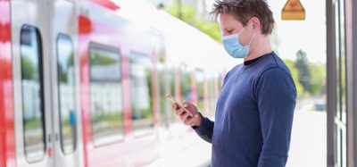 Man standing on train platform wearing face mask