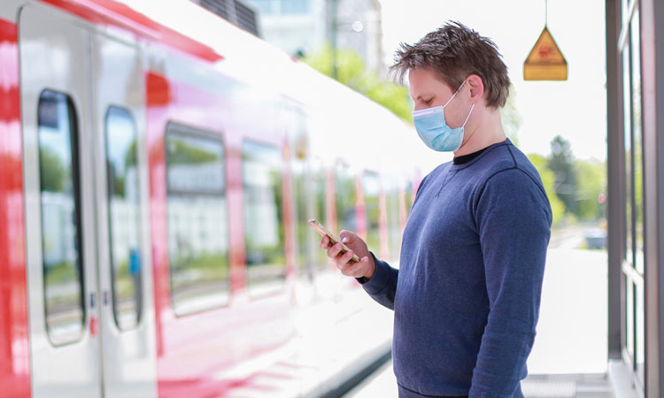 Man standing on train platform wearing face mask