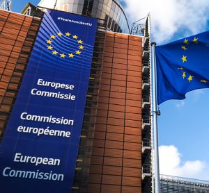 European Union flags waving in wind in front of European Commission building.