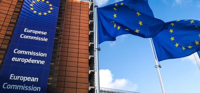 European Union flags waving in wind in front of European Commission building.