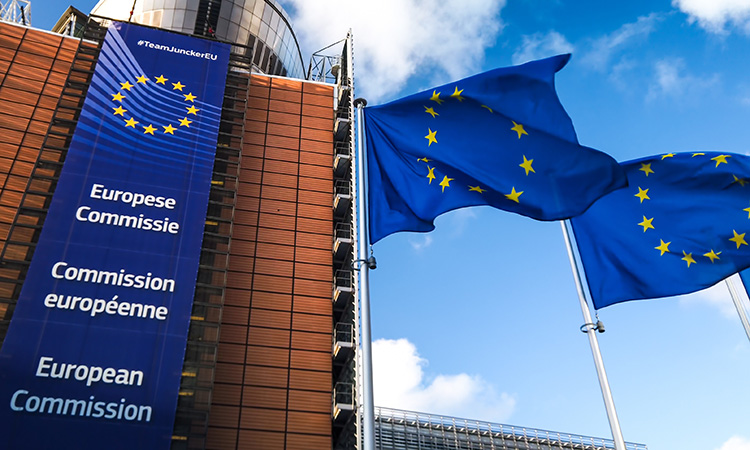 European Union flags waving in wind in front of European Commission building.