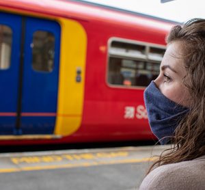 A woman wearing a mask at a train station to protect herself and others from catching and spreading COVID-19