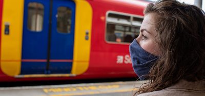 A woman wearing a mask at a train station to protect herself and others from catching and spreading COVID-19