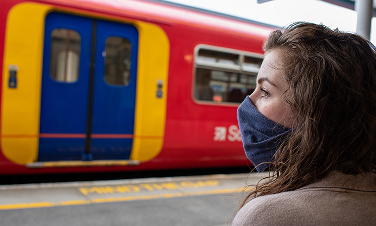 A woman wearing a mask at a train station to protect herself and others from catching and spreading COVID-19
