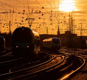 Trains arriving at Dortmund station in warm evening light, with the curved main line railway tracks glistening in the sun.