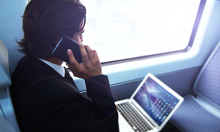 Businessman working with laptop on the way to work in train