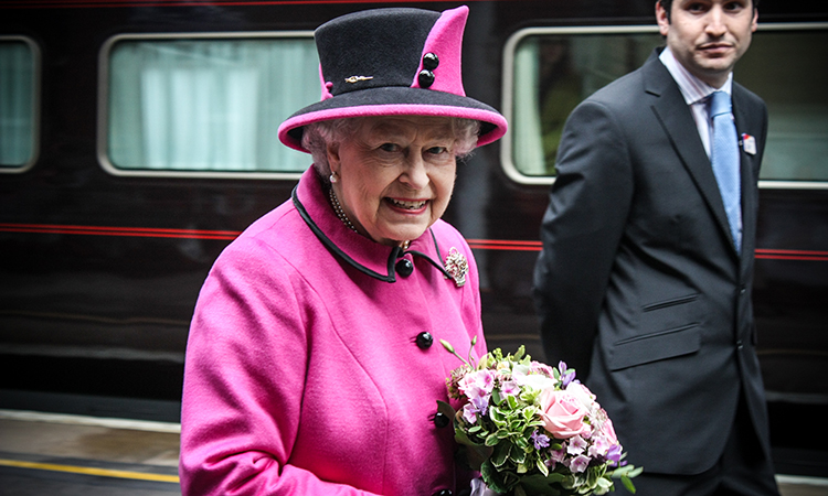 Queen Elizabeth II standing beside a train