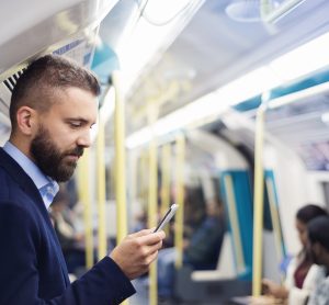 man holding phone out loud in an underground train.