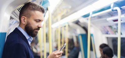 man holding phone out loud in an underground train.