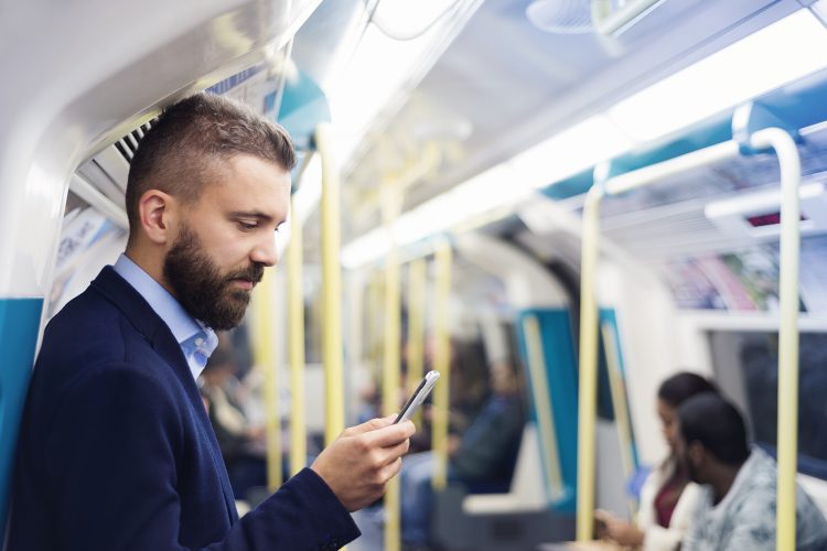 man holding phone out loud in an underground train.