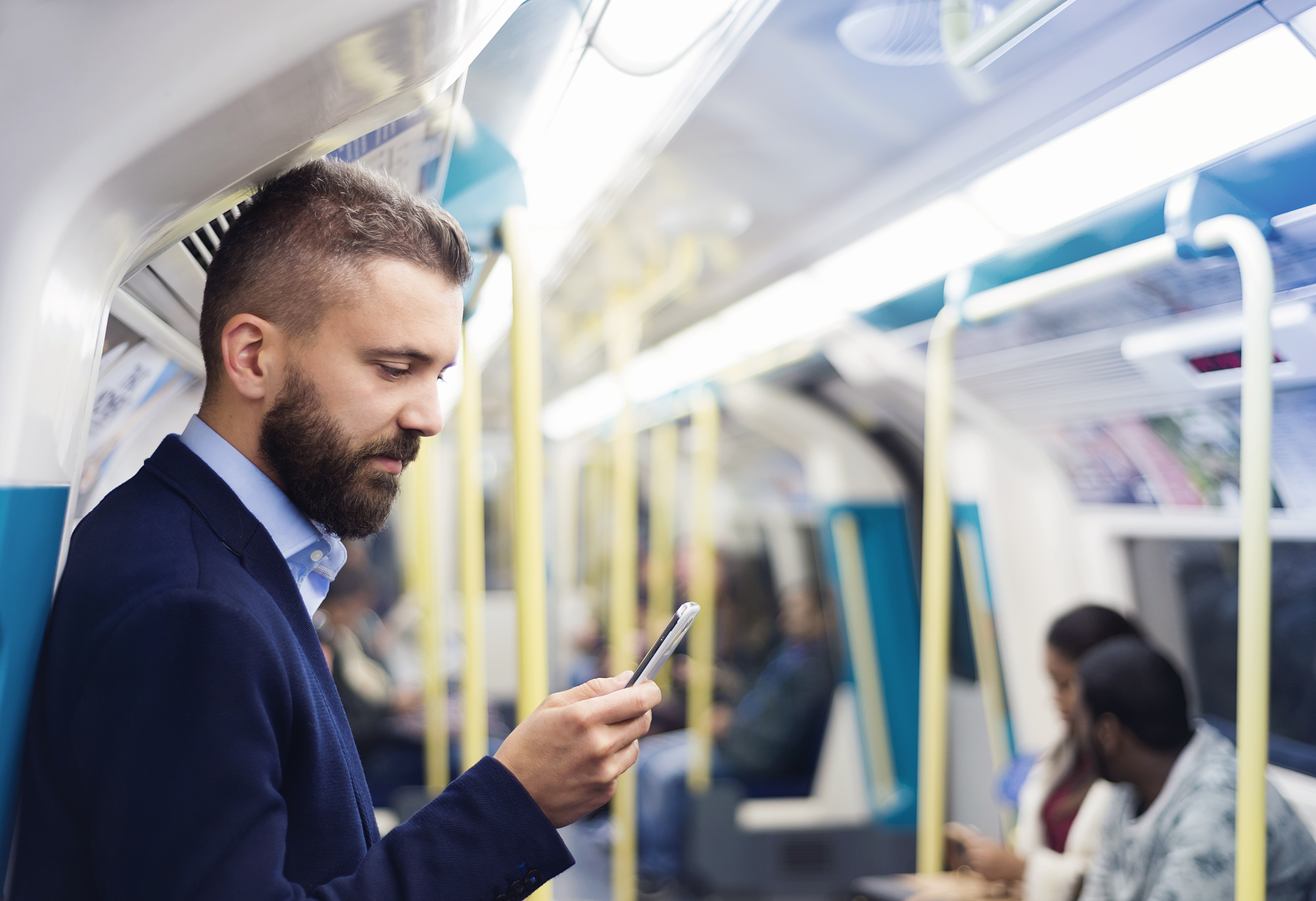 man holding phone out loud in an underground train.