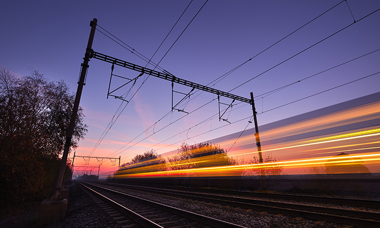 Passenger train on railroad tracks at the sunrise - blurred motion