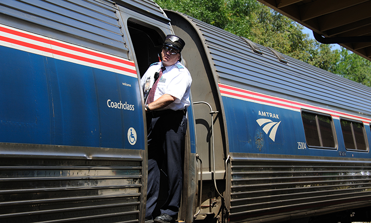 Railroad conductor on an Amtrak passenger train at Deland Railroad station in Florida.