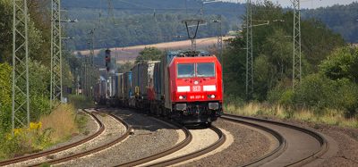 DB (Deutsche Bahn) Modern Locomotive with container wagons drives on tracks.